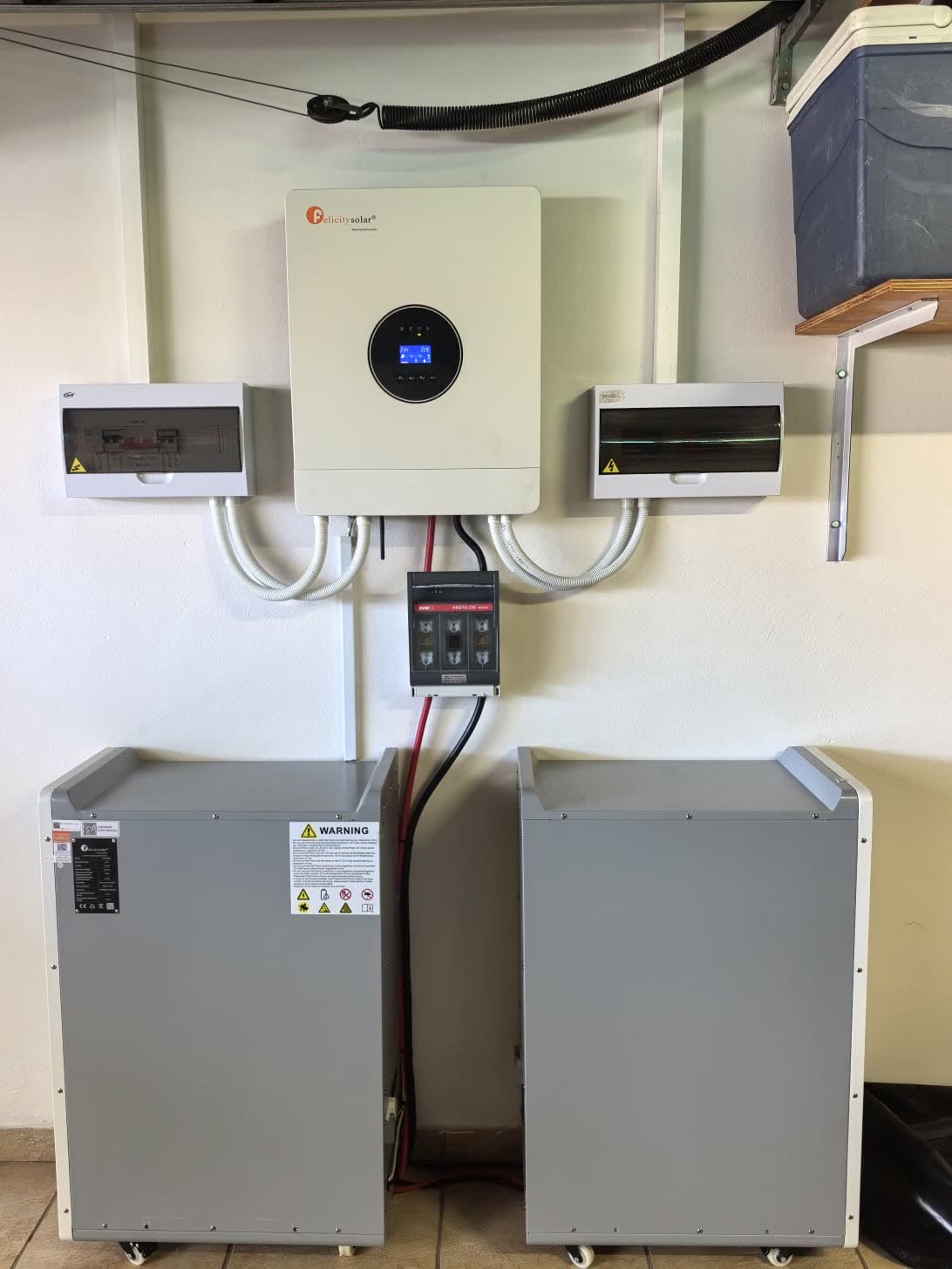 Solar inverter installed above two battery units mounted against a wall