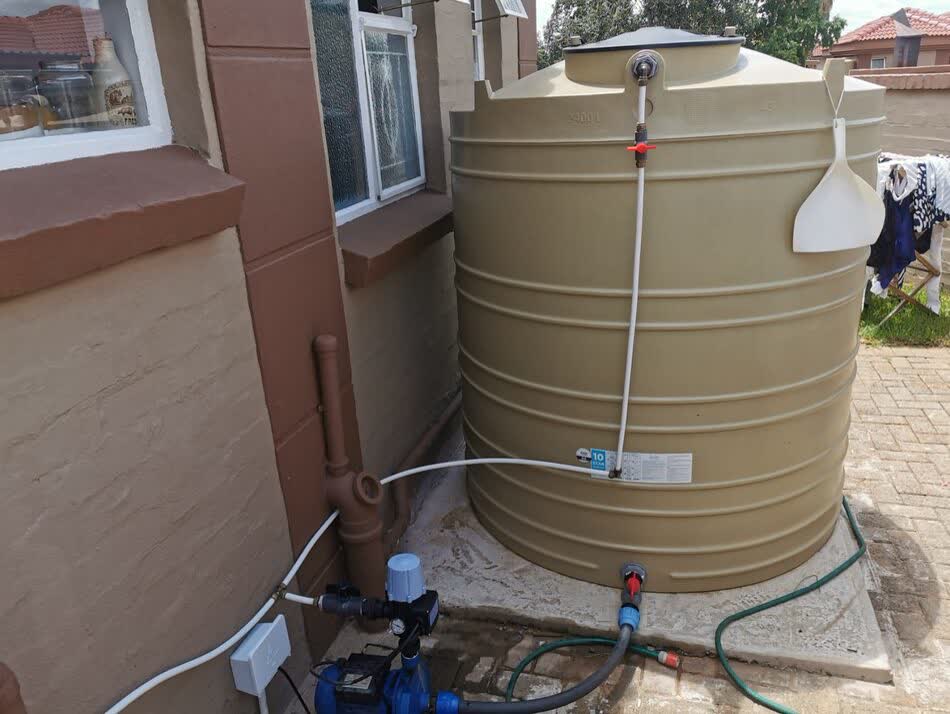 Water storage tank installed outside a house with pump and plumbing connections