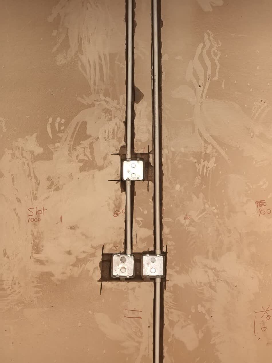 Electrical conduit and flush-mount boxes chased into a plastered wall before finishing
